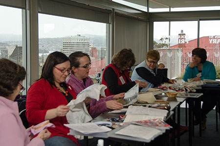 Guild members sitting at a table stitching and chatting during a stitching day